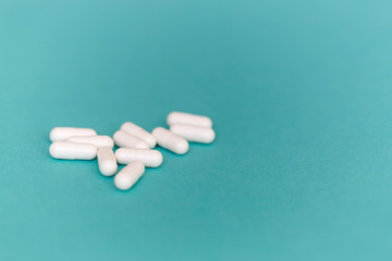 A heap of medicinal white capsules on a blue background. Free space for text. Medical background