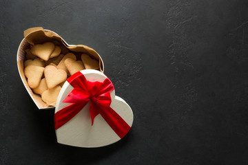 Valentines day greeting card. Homemade cookies in gift box heart shaped on black. Top view. Space...