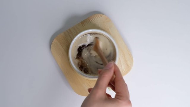 Top view of Person hand steering coffee in a cup with spoon. Breakfast morning of a cup hot black coffee on white background. Closeup Slow motion.