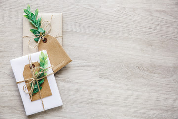 Composition with natural style handcrafted gift boxes, floral decor elements and rustic twine bow on wooden background.