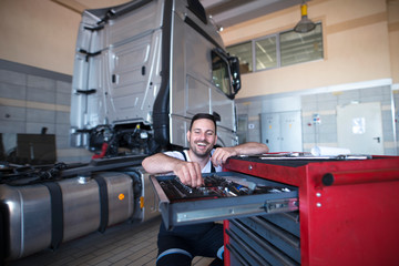 Truck mechanic and serviceman choosing tools for vehicle maintenance. Truck repair shop.