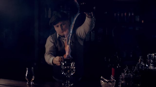 The bartender is preparing the punch "Blue Blazer". A stream of burning alcohol pours from a shaker into a shaker.