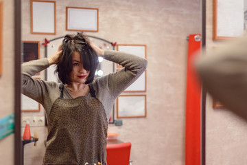 woman with black hair does her hair at the dressing table with a mirror