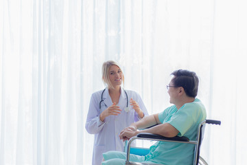 Nurse reassuring her patient on wheelchair in hospital / healthcare medical concept. copy space