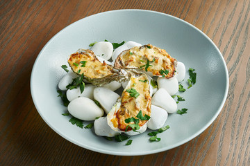 Baked oysters with cheese on the sea, hot stones on a wooden background. Healthy seafood. Film effect during post. Soft focus