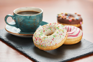 Cup of coffee and glazed doughnuts with sprinkles