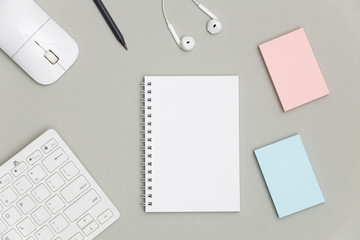 Blank spiral notebook with keyboard, supplies and pencil on gray background. Top view office desk with notepad. Creative flat lay photo