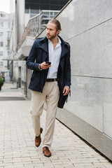 Attractive young bearded businessman walking outdoors