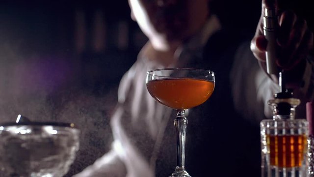 The bartender is preparing a cocktail "Rob Roy". Sprinkles smoky scotch whisky  on a cocktail glass. Maybe it's an Old Pal cocktail. Slow motion.