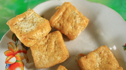 Blurred image out of focus fried tofu on a white plate, photographed with selective focus