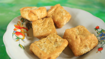 Blurred image out of focus fried tofu on a white plate, photographed with selective focus