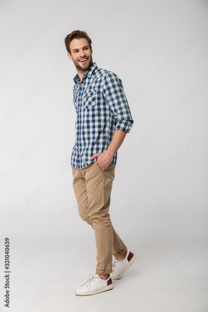 Wall mural portrait of laughing young man posing on camera with hands in pockets