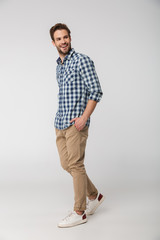 Portrait of laughing young man posing on camera with hands in pockets