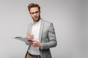 Portrait of thinking young man holding clipboard and writing