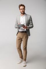 Portrait of thinking young man holding clipboard and writing