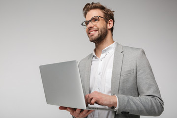 Portrait of smiling handsome man holding and using laptop