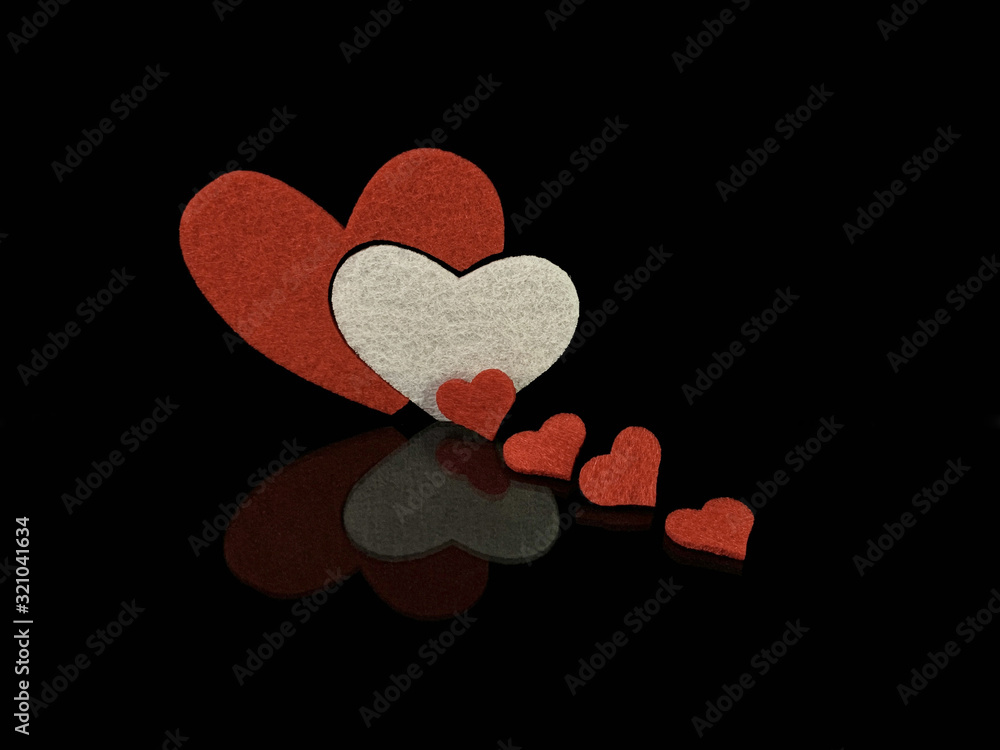Poster white and several red hearts on a black background. reflection of two hearts from a glossy surface. 