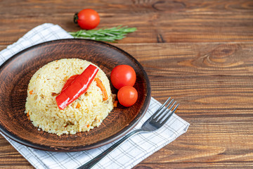 Rice with vegetables. Vegetarian dish. Mushrooms and carrots, onions, spices, hot chili peppers and garlic. Black pepper and zira. Cooking in olive oil. Healthy diet. On a wooden background.