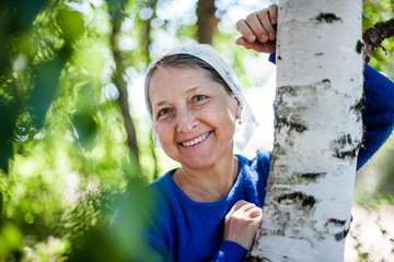  mature woman near birch trees in summer.