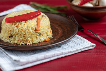 Rice with vegetables. Vegetarian dish. Mushrooms and carrots, onions, spices, hot chili peppers and garlic. Black pepper and zira. Cooking in olive oil. Healthy diet. On a wooden background.