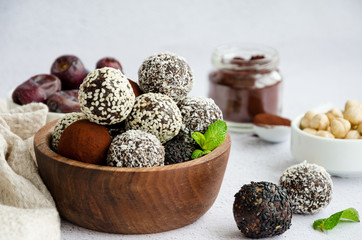 Energy balls. Truffles of dates, walnuts, hazelnuts and cocoa in a wooden bowl on a light...