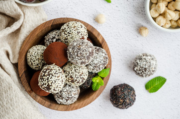 Energy balls. Truffles of dates, walnuts, hazelnuts and cocoa in a wooden bowl on a light background. Healthy dessert, sugar-free, gluten-free. Horizontal orientation. Top view, close up.