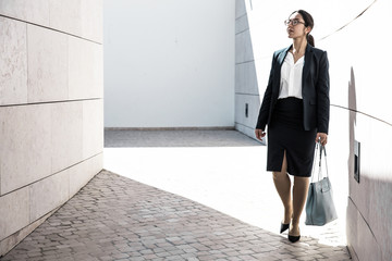 Serious business woman heading to work. Job candidate in formal suit and glasses searching employers office. Walking to office concept