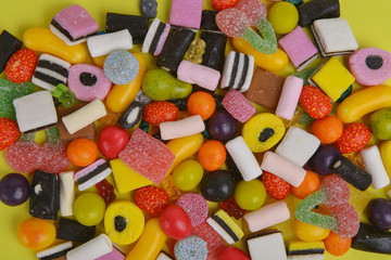Set with various colorful candies on a yellow background, top view. Close up of mixed sweets.