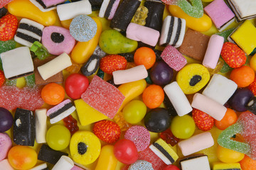 Set with various colorful candies on a yellow background, top view. Close up of mixed sweets.