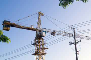 arrow of a construction crane on a construction site against the sky and trees