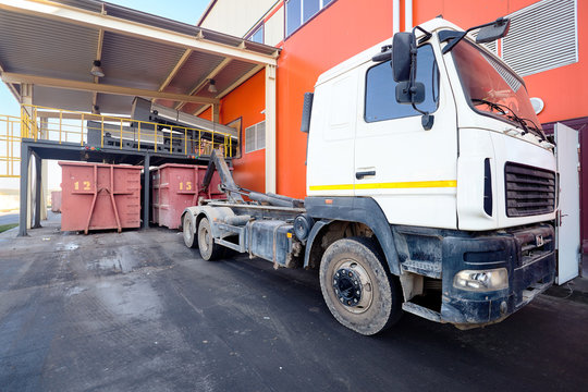 At modern waste recycling plant yard, process of loading sorted garbage from conveyor belt into container for further transportation by truck recycling or disposal