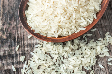 A bowl of white rice against the background of old boards near sprinkled rice. Jasmine rice for cooking.