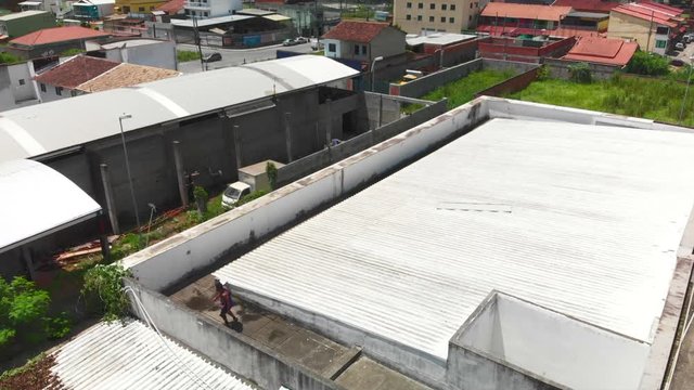 two young freeruners jumping and performing  flips and tricks over obstacles on a rooftop followed bya drone