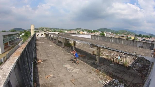 slow motion video of a young freerunner doing a cartwheel on a roof  of a abandoned building