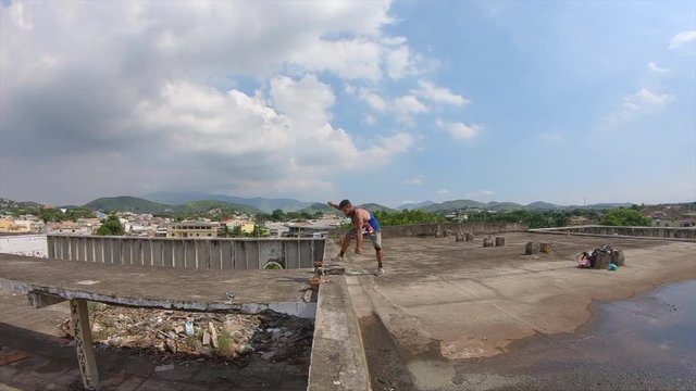 slow motion video of a young freerunner jumping a sideflip on a roof  of a abandoned building