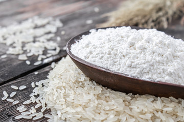 Rice flour in a bowl on a pile of white rice on old boards.