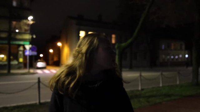 Lonely, sad, thoughtful girl walking alone in the street slow motion at night