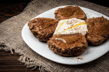 Chocolate pancakes with honey and yogurt on dark wooden background.