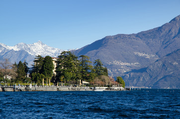 Fototapeta premium Sunlight over an Alpine Lake with Snow-capped Mountain in Lombardy, Italy.