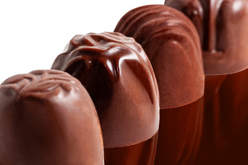 Sweet chocolate candy unwrapped in a row on dark background.