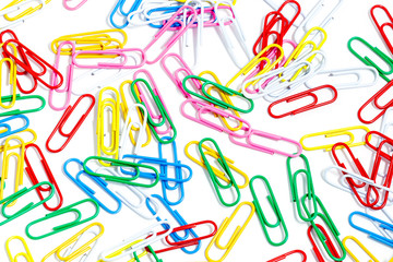 Fototapeta na wymiar Multicolored paper clips on a white background. Different color wire plugs for documents. Office supplies abstract concept.