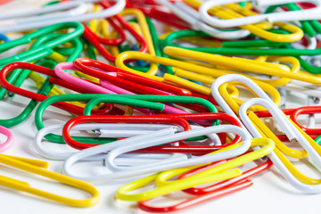 Multicolored paper clips on a white background. Different color wire plugs for documents. Office supplies abstract concept.