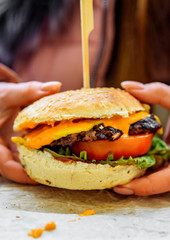 Woman hand holding a fresh burger before eating on street cafe