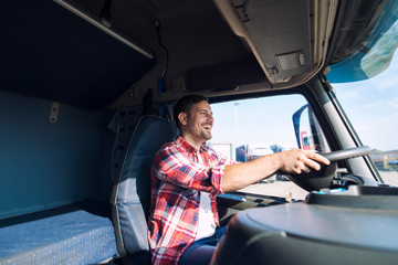 Professional middle aged truck driver in casual clothes driving truck vehicle and delivering cargo...