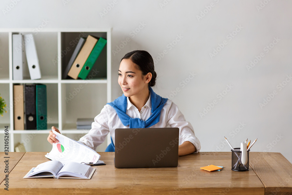 Wall mural Image of young asian woman using laptop computer while working in office