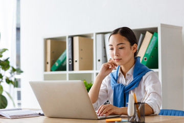 Image of young asian woman using laptop computer while working in office