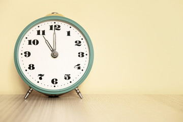 Antique analog clock with hands set at 11:00. 23:00 The alarm clock is on the table