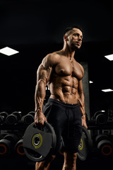 Fototapeta na wymiar Shirtless male bodybuilder carrying weights.