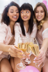 selective focus of multicultural girls clinking with glasses of champagne on bachelorette party
