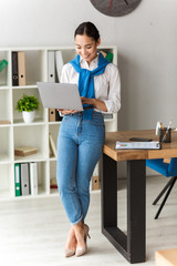 Image of asian secretary woman holding laptop while working in office
